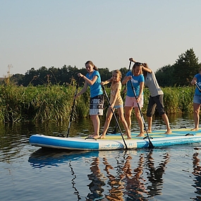 Personen stehen auf einem Stand-Up-Paddle-Board.