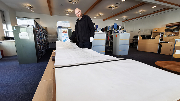 Somin Kursawe zeigt ein großes Buch in der Bibliothek.