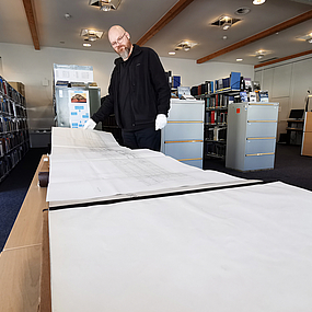 Somin Kursawe zeigt ein großes Buch in der Bibliothek.