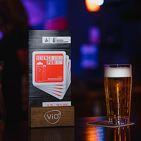 Ein Bierglas auf der Theke mit dem Science goes Public-Logo.