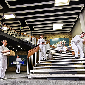 Schauspieler führen eine Szene auf einer Treppe im Columbusbahnhof auf.